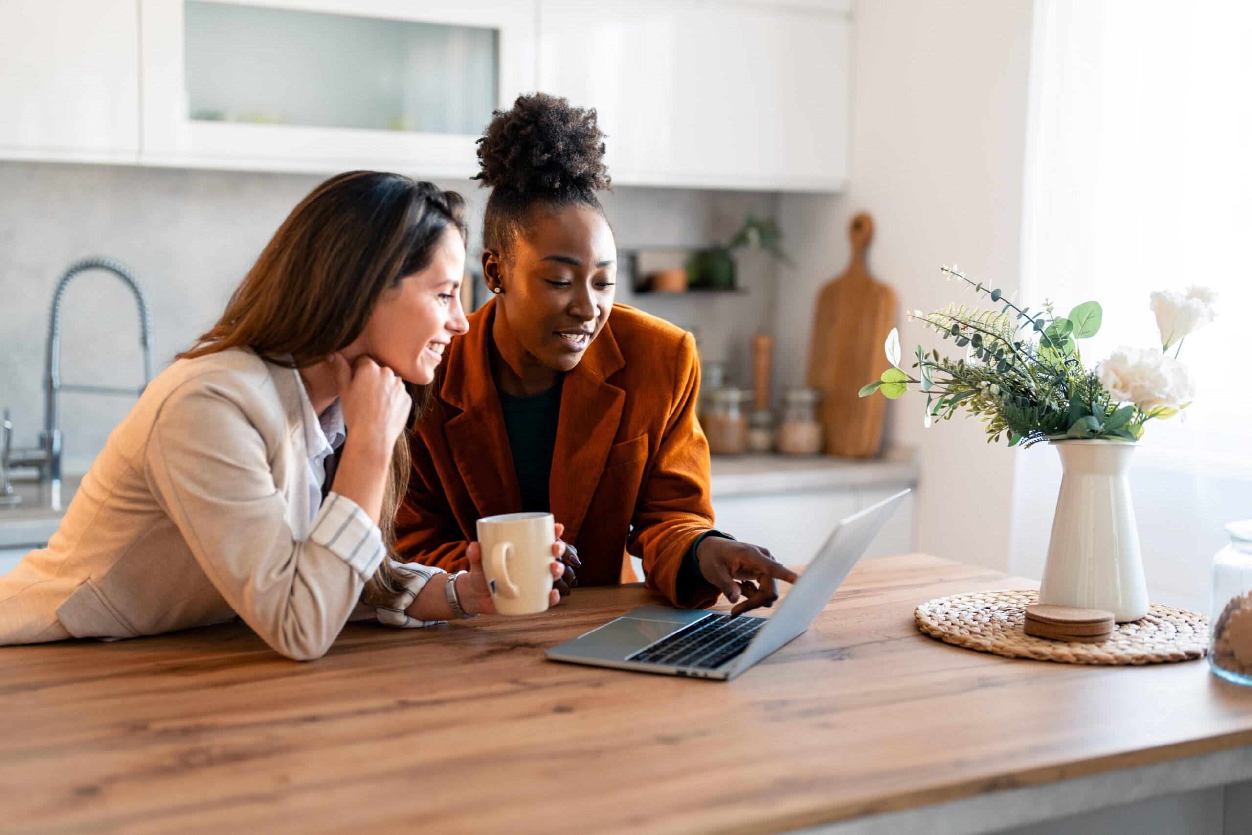 Two women in the kitchen looking at a laptop